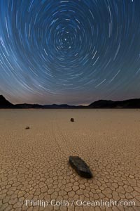 Racetrack sailing stone and star trails.  A sliding rock of the Racetrack Playa. The sliding rocks, or sailing stones, move across the mud flats of the Racetrack Playa, leaving trails behind in the mud. The explanation for their movement is not known with certainty, but many believe wind pushes the rocks over wet and perhaps icy mud in winter