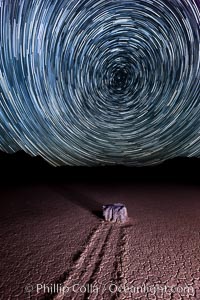 Racetrack sailing stone and star trails.  A sliding rock of the Racetrack Playa. The sliding rocks, or sailing stones, move across the mud flats of the Racetrack Playa, leaving trails behind in the mud. The explanation for their movement is not known with certainty, but many believe wind pushes the rocks over wet and perhaps icy mud in winter, Death Valley National Park, California