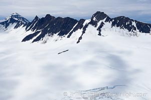 The Kenai Mountains rise above thick ice sheets and the Harding Icefield which is one of the largest icefields in Alaska and gives rise to over 30 glaciers, Kenai Fjords National Park