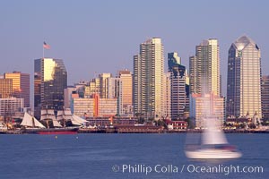 San Diego city skyline at dusk, viewed from Harbor Island, a sailboat cruises by in the foreground, the Star of India at left.