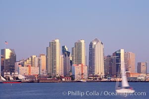 San Diego city skyline at dusk, viewed from Harbor Island, a sailboat cruises by in the foreground, the Star of India at left