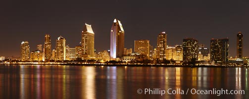 San Diego city skyline at night, showing the buildings of downtown San Diego reflected in the still waters of San Diego Harbor, viewed from Coronado Island.  A panoramic photograph, composite of seven separate images