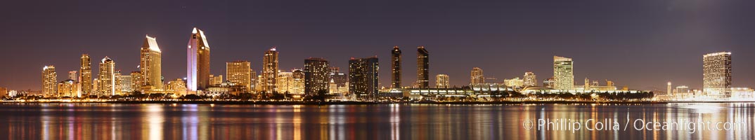 San Diego city skyline at night, showing the buildings of downtown San Diego reflected in the still waters of San Diego Harbor, viewed from Coronado Island.  A panoramic photograph, composite of five separate images.