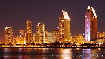 San Diego city skyline at night, showing the buildings of downtown San Diego reflected in the still waters of San Diego Harbor, viewed from Coronado Island.