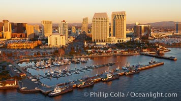 San Diego Marina District, sunset, with fishing vessels docked alongside pier, Seaport Village (right) and downtown highrise office buildings rising over San Diego Bay
