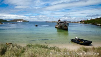 Sand beach at New Island Settlement, with zodiac ashore and shipwrreck