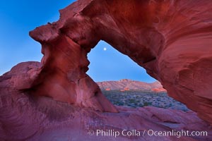 Natural arch formed in sandstone frames the setting moon, Valley of Fire State Park