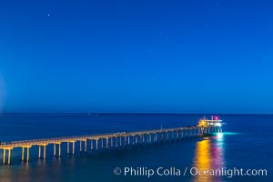 Scripps Institution of Oceanography Research Pier at night, lit with stars in the sky, old La Jolla town in the distance.