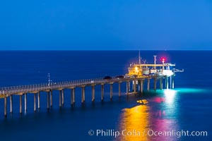 Scripps Institution of Oceanography Research Pier at night, lit with stars in the sky, old La Jolla town in the distance.