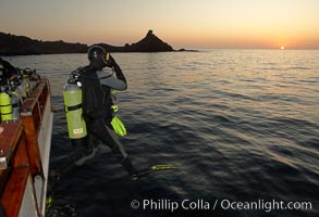 A SCUBA diver leaps into the water, from boat Horizon, into the kelp forest and rich waters of San Clemente Island, China Hat Point, Balanced Rock, sunrise