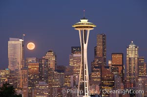 Full moon rises over Seattle city skyline at dusk, Space Needle at right.