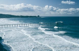 Scripps Institution of Oceanography research piers extends out beyond the waves, with La Jolla in the distance