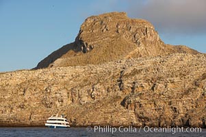 Wolf Island, with a liveaboard tour boat below sheer seacliffs, is the largest of the islands in the distant northern island group of the Galapagos archipelago, is home to hundreds of thousands of seabirds.  Vast schools of sharks and fish inhabit the waters surrounding Wolf Island.