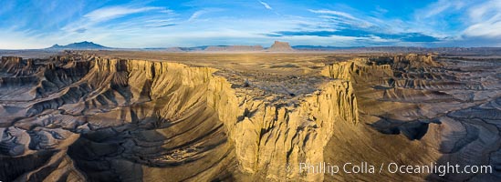 Skyline Rim promontory aerial panoramic photo, with Factory Butte in the distance. The Henry Mountains are in the far left.  The Blue Hills lie below the mesa.  Just after sunrise. Utah badlands
