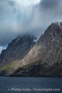 South Georgia Island coastline, showing the island's characteristic rugged topography.  56% of the island is covered by 161 glaciers, which have created numerous large bays and inlets that provide excellent habitat for marine animals and seabirds. Mountains meet the sea in steep-sided seacliffs covered with sparse vegetation.  The highest point on South Georgia Island is Mt. Paget at 2,915m