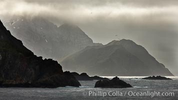 South Georgia Island coastline, showing the island's characteristic rugged topography.  56% of the island is covered by 161 glaciers, which have created numerous large bays and inlets that provide excellent habitat for marine animals and seabirds. Mountains meet the sea in steep-sided seacliffs covered with sparse vegetation.  The highest point on South Georgia Island is Mt. Paget at 2,915m