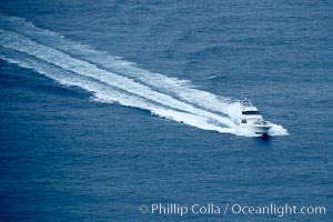 Sport fishing boat cruises across the ocean, leaving a long wake in its path