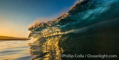 Sunrise glints yellow on breaking wave, dawn surf, The Wedge, Newport Beach, California