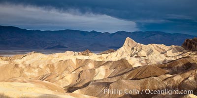 Sunrise at Zabriskie Point, Manly Beacon is lit by the morning sun while dark clouds lie on the horizon.