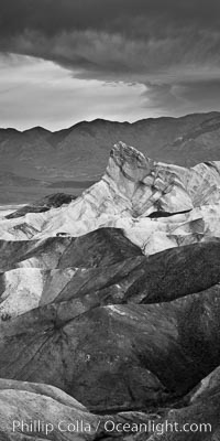 Sunrise at Zabriskie Point, Manly Beacon is lit by the morning sun while dark clouds lie on the horizon, Death Valley National Park, California