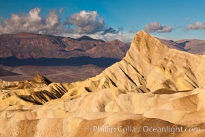 Sunrise at Zabriskie Point, Manly Beacon is lit by the morning sun while clouds from a clearing storm pass by, Death Valley National Park, California