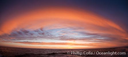 Sunset clouds create a colorful arch, spanning the heavens from horizon to horizon, over the open sea between the Falkland Islands and South Georgia Island