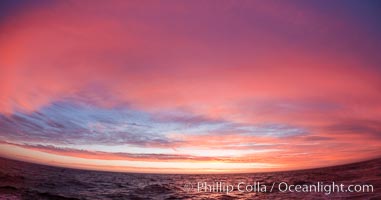 Sunset clouds create a colorful arch, spanning the heavens from horizon to horizon, over the open sea between the Falkland Islands and South Georgia Island