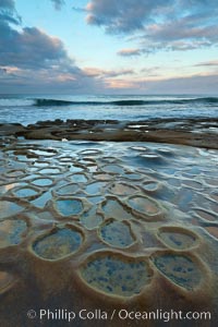 Waves wash over sandstone reef, clouds and sky, La Jolla, California