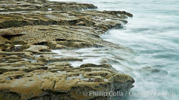 Waves wash over sandstone reef, clouds and sky, La Jolla, California