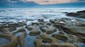 Waves wash over sandstone reef, clouds and sky, La Jolla, California