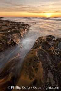 Waves wash over sandstone reef, clouds and sky.