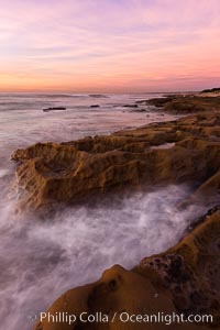 Waves wash over sandstone reef, clouds and sky.