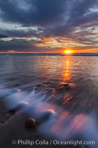 Surf and sky at sunset, waves crash upon the sand at dusk, Carlsbad, California