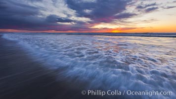 Surf and sky at sunset, waves crash upon the sand at dusk, Carlsbad, California