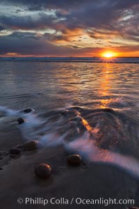 Surf and sky at sunset, waves crash upon the sand at dusk, Carlsbad, California