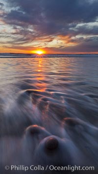 Surf and sky at sunset, waves crash upon the sand at dusk, Carlsbad, California