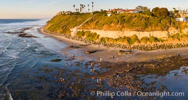 Swamis Beach Reefs Exposed by King Tides, people explore ocean reefs normally underwater but exposed on the extreme low tides known as King Tides. Aerial photo, Encinitas, California