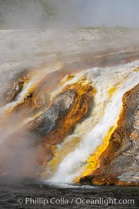 Thermophilac heat-loving bacteria color the runoff canals from Excelsior Geyser as it empties into the Firehole River, Midway Geyser Basin, Yellowstone National Park, Wyoming