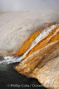 Thermophilac heat-loving bacteria color the runoff canals from Excelsior Geyser as it empties into the Firehole River, Midway Geyser Basin, Yellowstone National Park, Wyoming