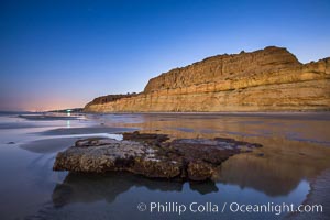 Torrey Pines Cliffs lit at night by a full moon, low tide reflections.