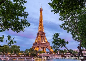 La Tour Eiffel at dusk over the River Seine in Paris France. The Eiffel Tower is an iron lattice tower located on the Champ de Mars in Paris, named after the engineer Gustave Eiffel, who designed the tower in 1889 as the entrance arch to the 1889 World's Fair. The Eiffel tower is the tallest structure in Paris and the most-visited paid monument in the world