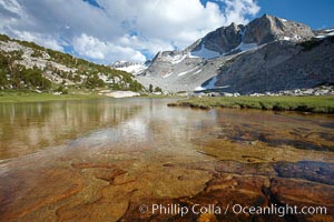 Townsley Lake (10396'), a beautiful alpine lake sitting below blue sky, clouds and Fletcher Peak (right), lies amid the Cathedral Range of glacier-sculpted granite peaks in Yosemite's high country, near Vogelsang High Sierra Camp.