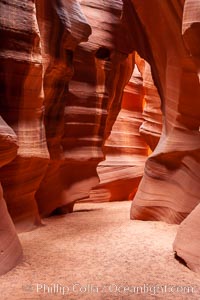 A hiker admiring the striated walls and dramatic light within Antelope Canyon, a deep narrow slot canyon formed by water and wind erosion, Navajo Tribal Lands, Page, Arizona