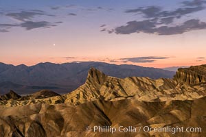 Venus sets over Manley Beacon and the Panamint Mountains, viewed from Zabriskie Point, landscape lit by a full moon, evening, stars