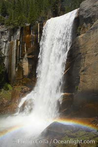 Vernal Falls at peak flow in late spring, with a rainbow appearing in the spray of the falls. Yosemite National Park.