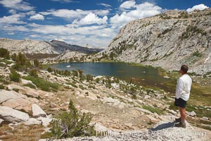 Hiker views Vogelsang Lake and the western buttress of Fletcher Peak from a vantage point near Vogelsang Pass, looking north, Yosemite National Park, California