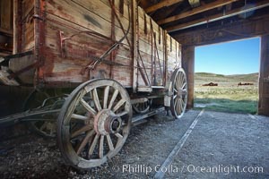 Wagon and interior of County Barn, Brown House and Moyle House in distance, Bodie State Historical Park, California