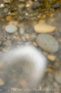 Water flows past beach cobblestones, blur.