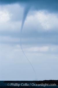 The early stage of a waterspout, in which a funnel descends from clouds down toward the ocean surface.  Note the thin curved vortex of the waterspout, it is not yet mature.  Waterspouts are tornados that form over water