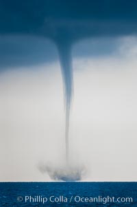 A mature waterspout, seen extending from clouds above to the ocean surface.  A significant disturbance on the ocean is clearly visible, the waterspout has reached is maximum intensity.   Waterspouts are tornadoes that form over water, Great Isaac Island